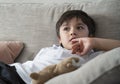 Child putting finger in his mouth. Schoolboy biting his finger nails while watching TV, Emotional kid portrait, Young boy siting Royalty Free Stock Photo