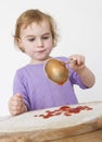 Child putting sieved tomatoes on dough