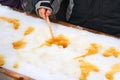 Child putting on a stick maple taffy