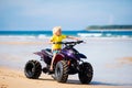 Child on quad bike at beach. All-terrain vehicle. Royalty Free Stock Photo