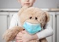 Child on quarantine due epidemic of coronavirus COVID-19. Child girl cuddle toy bear wear medical mask Royalty Free Stock Photo