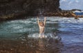 Child raises her hands up in the water and splashes water drops on sea. Kids summer vacation and travel concept.