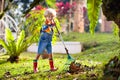 Child and rake in autumn garden. Kid raking leaves Royalty Free Stock Photo