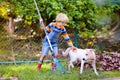 Child and rake in autumn garden. Kid raking leaves Royalty Free Stock Photo