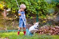 Child and rake in autumn garden. Kid raking leaves Royalty Free Stock Photo