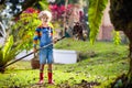 Child and rake in autumn garden. Kid raking leaves Royalty Free Stock Photo