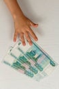 The child reaches for money lying on wooden table