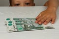 The child reaches for money lying on a wooden table