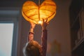 child reaching for a heartshaped pendant lamp