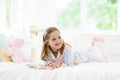 Child reading book in bed. Kids read in bedroom Royalty Free Stock Photo