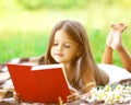 Child reading a book on the grass