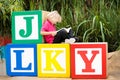 Child reading book in school yard. Kid learning abc letters. Little boy sitting on wooden toy blocks with alphabet in preschool or Royalty Free Stock Photo