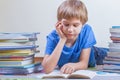 Child reading book between the stacks of books.