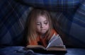 Child reading a book under the covers. Immersion into the magical world Royalty Free Stock Photo