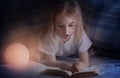 Child reading a book under the covers. Immersion into the magical world Royalty Free Stock Photo