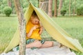 Boy playing video game outdoor in park, backyard, garden. Kid with phone in tent. 6 years old child having fun on nature Royalty Free Stock Photo