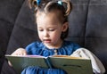 Child reading. Little cute girl 1-3 is reading a book with a toy plush hare sitting on a sofa Royalty Free Stock Photo