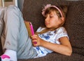 Cute girl kid using iPad digital computer tablet on bed for education or playing game. Royalty Free Stock Photo