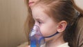 The child is receiving respiratory therapy with a nebulizer. Mommy inhales a little girl in a mask with a nebulizer at Royalty Free Stock Photo