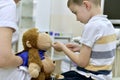 The child at the reception at the clinic examines the mouth cavity with a medical spatula of a toy plush monkey Royalty Free Stock Photo