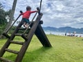 Ilhabela, SÃ£o Sebastiao, Brazil, 05 january, 2023: Child in a red blouse climbing the stairs of a slide in a park on the beach. Royalty Free Stock Photo