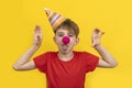 Child with red clown nose on yellow background. Cheerful clown boy . 1 April Fools day concept