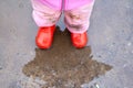 The child in red gumboots costs in an autumn pool