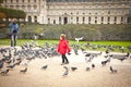Child in a red jacket running around among flocks of pigeons Royalty Free Stock Photo