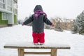Child with red pants standing wooden bench snow