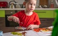 Child in a red T-shirt paints with colorful watercolors at the table Royalty Free Stock Photo