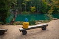 The child is resting on a bench by a beautiful turquoise lake