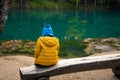 The child is resting on a bench by a beautiful turquoise lake