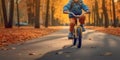 Child rides a bike in city park. Small child is learning to ride a bike on an asphalt road in the autumn forest. Generative AI Royalty Free Stock Photo