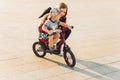 Child rides a bike while his mother walks beside him. Happy mother teaches her son to ride a bike in the park Royalty Free Stock Photo