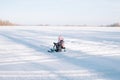 Child rides snowcat on snowy road. Little girl in pink warm jacket enjoys walk in nature and sledding on frozen river on