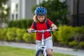 Child riding bicycle. Little kid boy in helmet on bicycle along bikeway. Happy cute little boy riding bicycle in summer