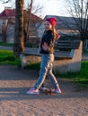 Child riding on kickscooter alone. Blonde cute girl on scooter on spring city park street background. Active lifestyle