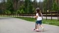 Child riding scooter. Happy little kid girl playing pink kick board on road in park outdoors on summer day, Active children games