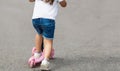 Child riding scooter. Happy little kid girl playing pink kick board on road in park outdoors on summer day, Active children games