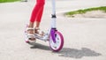 Child riding scooter. Happy little kid girl playing pink kick board on road in park outdoors on summer day, Active children games Royalty Free Stock Photo