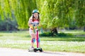 Child riding kick scooter in summer park. Royalty Free Stock Photo