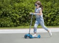 Child riding scooter. Kid on colorful kick board. Active outdoor fun for kids. Summer sports for preschool children. Little happy Royalty Free Stock Photo