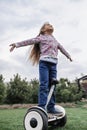 Child riding on self-balancing hover board on the backyard of cottage, outdoor kids activity