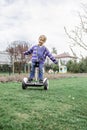 Child riding on self-balancing hover board on the backyard of cottage, outdoor kids activity