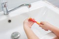 The child rinses toothbrush under running water Royalty Free Stock Photo