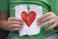 Child ripping red heart on a piece of paper