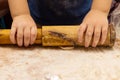 A child rolls dough for dumplings in a rustic kitchen. The concept of home cooking. Selective focus. Children`s hands