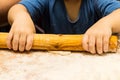 A child in rolls out the dough with a wooden rolling pin on a floured wooden board. Cooking with children, cooking at Royalty Free Stock Photo