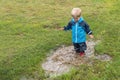 A child in rubber boots stands in a dirty puddle. Children`s pranks