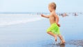 Child run with splashes by water pool along sea surf Royalty Free Stock Photo